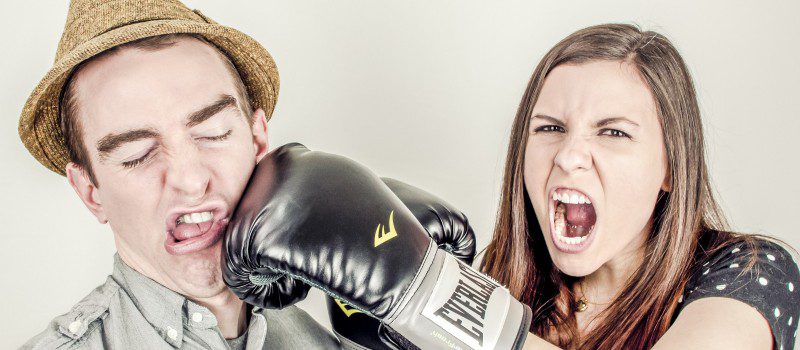 woman wearing boxing gloves punching a man