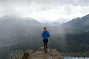 woman on the edge of a mountain looking at her surroundings