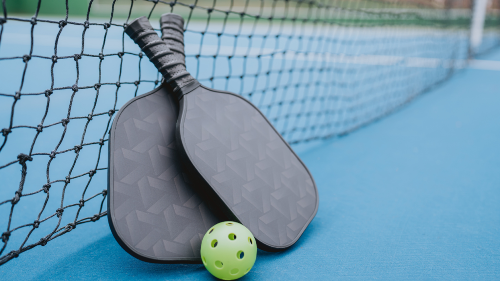 two black pickleball paddles leaning on a net