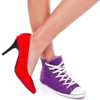 Woman wearing red high heel shoe on one leg and sport shoe on another leg